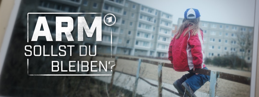 Ein kleines Mädchen sitzt auf einem Holzgeländer eines Spielplatzes im Innenhof einer Plattenbau Siedlung.