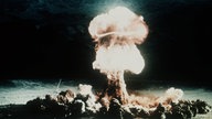 Ein Atompilz steigt nach der Explosion einer Atombombe über dem Testgelände in der Wüste von Nevada auf