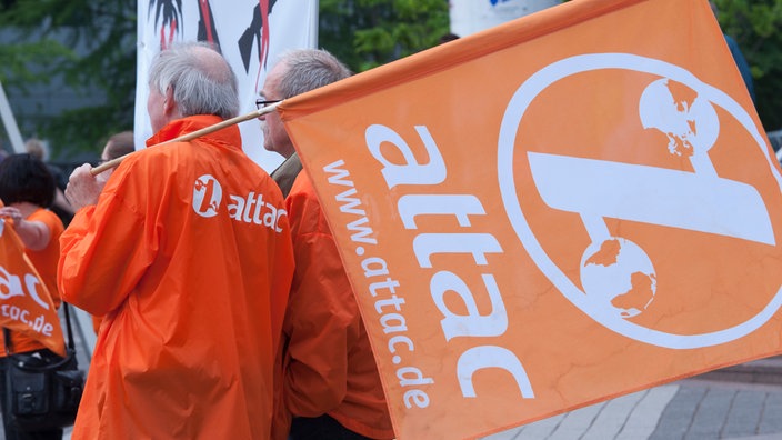 Attac-Aktivist trägt die orange Attacfahne