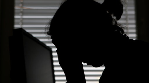 Eine Frau legt ihren Kopf in die Hände.