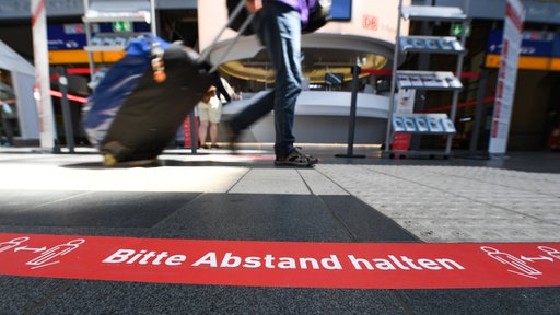 Ein Klebeband mit der Aufschrift "Bitte Abstand halten" ist im Frankfurter Hauptbahnhof am Boden aufgeklebt.