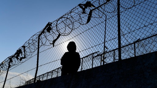 Ein Migrant sitzt neben einem Zaun des Flüchtlingslagers Moria.