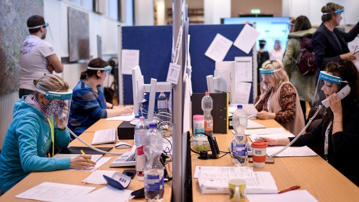 Mitarbeiter*innen telefonieren im Gesundheitsamt Berlin-Mitte.