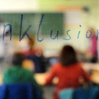 Symbolbild: Schriftzug "Inklusion" vor dem Motiv eines Klassenzimmers.