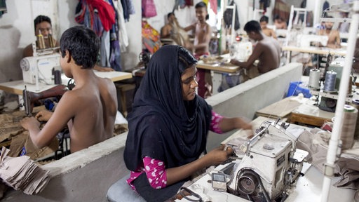 Eine Frau und mehrere Kinder nähen Kleidung in der bangladeschischen Stadt Dhaka.
