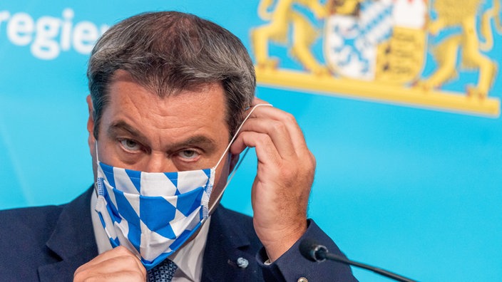 Markus Söder (CSU) setzt sich nach einer Pressekonferenz zur aktuelle Entwicklungen an den Corona-Teststationen für Reiserückkehrer seine Gesichtsmaske auf.