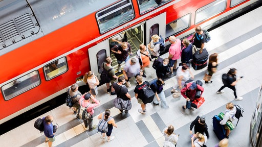 Menschen steigen in eine Regionalbahn ein - Blick aus der Vogelperspektive. 
