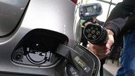 Ein Mann hält ein Ladekabel neben einem Mercedes-Benz GLC 300e Plug-In-Hybrid.