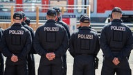 Bundespolizisten stehen auf einem Übungsgelände vor einem restaurierten Doppelstock-Waggon.