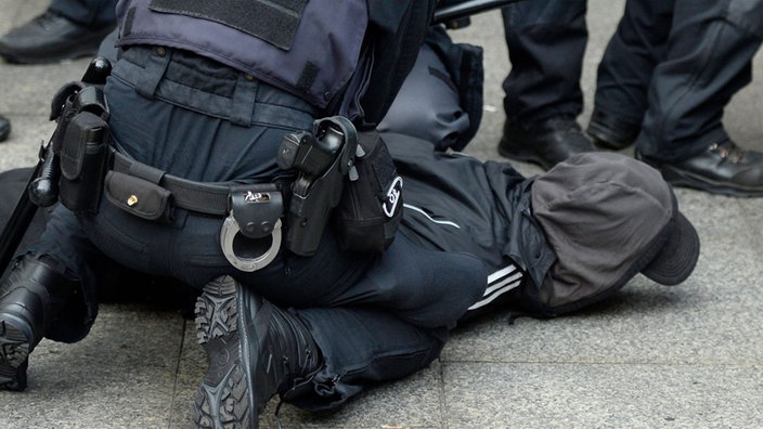 Polizisten fixieren einen Mann auf dem Boden