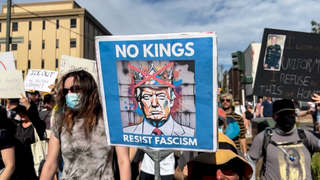 Bei einem Protest gegen Trump wird ein Plakat mit der Aufschrift "NO KINGS" hochgehalten.