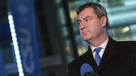 Markus Söder hinter einer Glastür mit CSU-Schriftzug