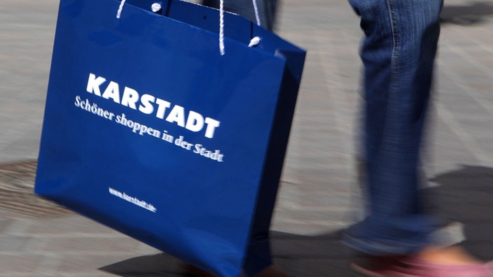 Eine Einkaufstüte von Karstadt an der Hand eine Einkäufers