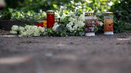 Kerzen und Blumen liegen auf einem Parkplatz an der Unfallstelle in Dinslaken