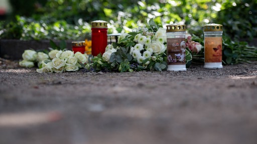 Kerzen und Blumen liegen auf einem Parkplatz an der Unfallstelle in Dinslaken