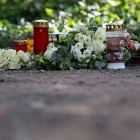 Kerzen und Blumen liegen auf einem Parkplatz an der Unfallstelle in Dinslaken
