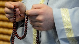 Ein Imam hält eine Gebetskette in der Hand 
