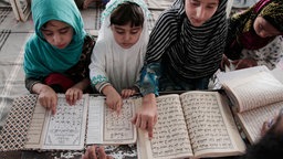 Mädchen in traditioneller Kleidung studieren den Koran