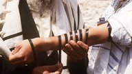 Einem jüdischen Gläubigen werden Gebetsriemen um den Arm gebunden