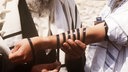 Einem jüdischen Gläubigen werden Gebetsriemen um den Arm gebunden