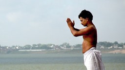 Ein Mann steht am Ganges und betet