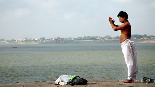 Ein Mann steht am Ganges und betet