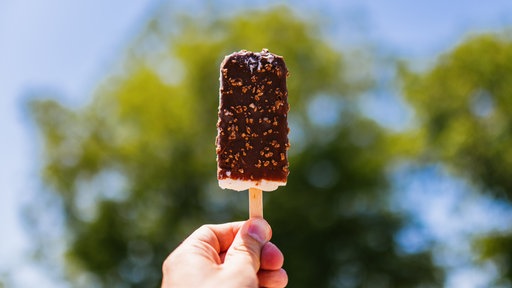 Eine Hand hält ein Eis am Stiel
