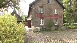 Steinerner Bau, dreigeschossig mit Satteldach, Aufschrift auf Mauer: Fährhaus Rote Mühle