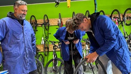 Zwei Jungs in der Fahrradwerkstatt die an einem Fahrrad werkeln