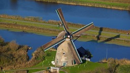 Eine Windmühle steht an einem Seitenarm des Rheins.