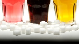 Zuckerwürfel und drei Gläser mit bunten Softdrinks