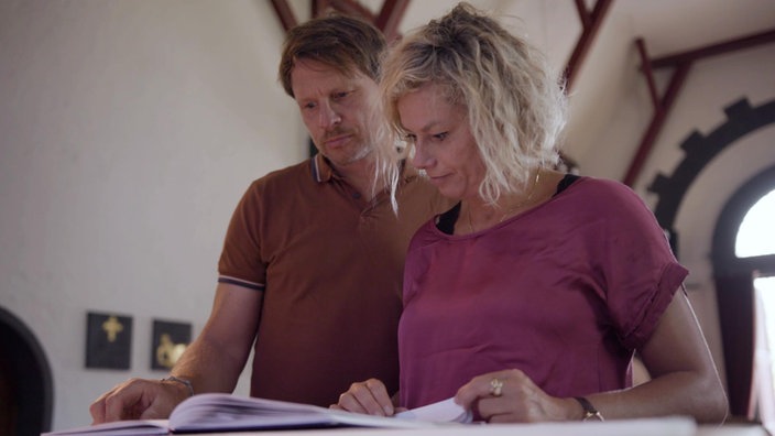 Mann und Frau gucken zusammen in ein Buch.