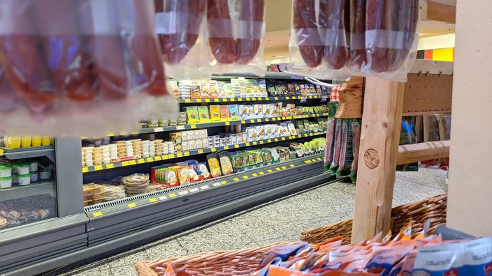 Ein Supermarktregal mit Fleischersatzprodukten. Im Vordergrund sind tierische Fleischwaren zu sehen.