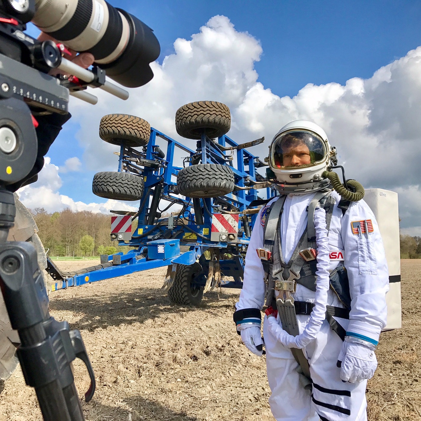 Astronaut auf einem Acker, davor eine Fernsehkamera