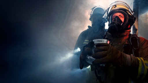 Feuerwehrmänner im Nebel und vor schwarzem Hintergrund