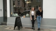 Zwei Frauen lehnen am Schaufenster, darauf die Schrift "Lebenslicht"