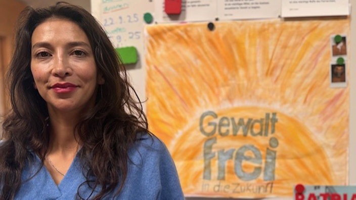 Stefanie Knaab steht vor einem Schild mit der Aufschrift: Gewaltfrei in die Zukunft