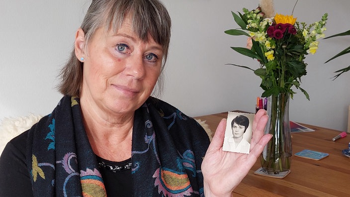 Lily Kurtićs schaut in die Kamera und hält ein Foto von ihrer Mutter in der Hand