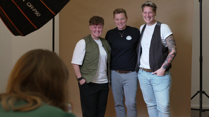 Drei Frauen stehen in einem Fotostudio und lächeln in die Kamera.