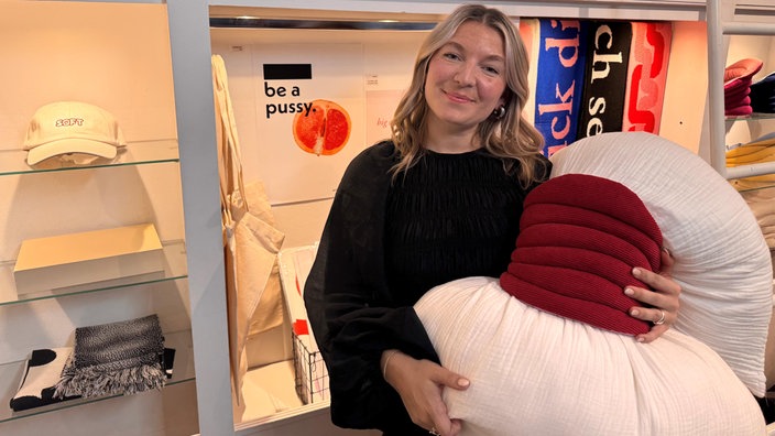 Porträtbild von Sanja. Sie lächelt in die Kamera und hat einen Masturbationssattel in der Hand. 