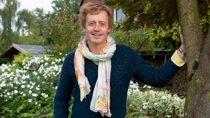 Florist Björn Kroner lehnt an Baum
