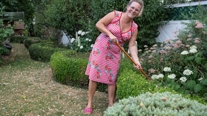Kai Judith Wetzel mit einem Rechen in ihrem Garten. 