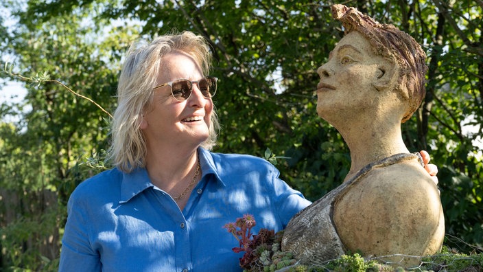 Petra Wichert mit einer Skulptur in ihrem Garten. 