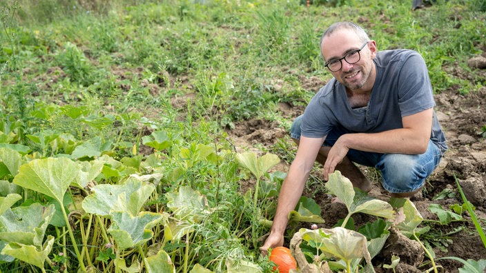 Torben Sauerland in seinem Garten mit Kürbis. 