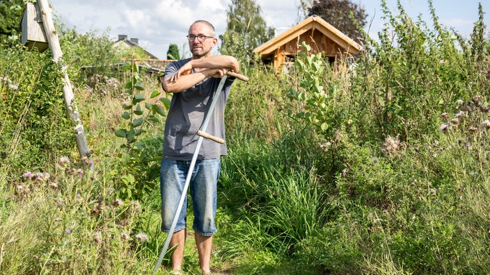 Torben Sauerland mit einer Sense. 