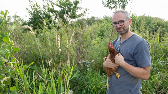 Torben Sauerland mit Huhn auf dem Arm.