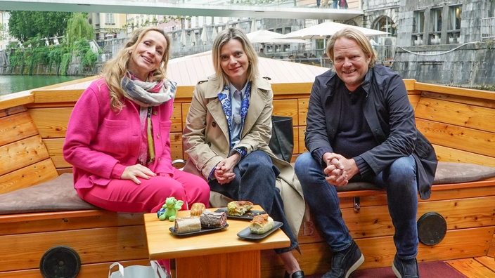 Tamina Kallert, Björn Freitag und Gastgeberin Valentina erkunden Ljubljana vom Wasser aus, inklusive Struklji-Verkostung an Bord.