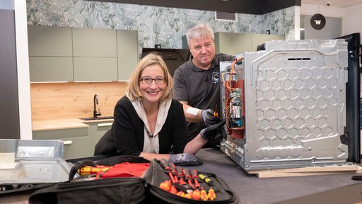 Jürgen Winter (r) zeigt Hauswirtschaftsmeisterin Yvonne Willicks, was man am Backofen alles selbst reparieren kann und was besser der Fachmann übernehmen sollte.