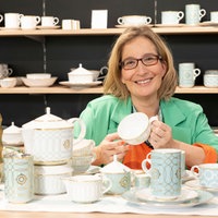 Yvonne Willicks sitzt in einem Raum voller verschiedener Tassen.