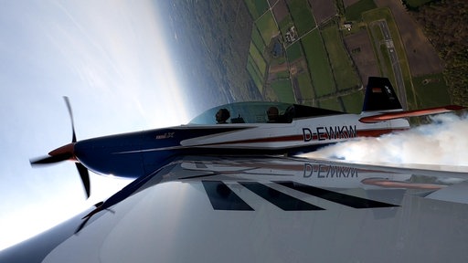 Nahaufnahme: Ein Sportflugzeug macht einen Looping.